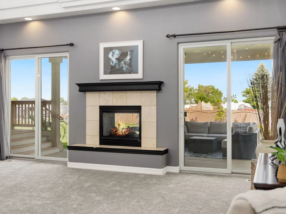 Family room with two white sliding glass patio doors on either side of a fireplace